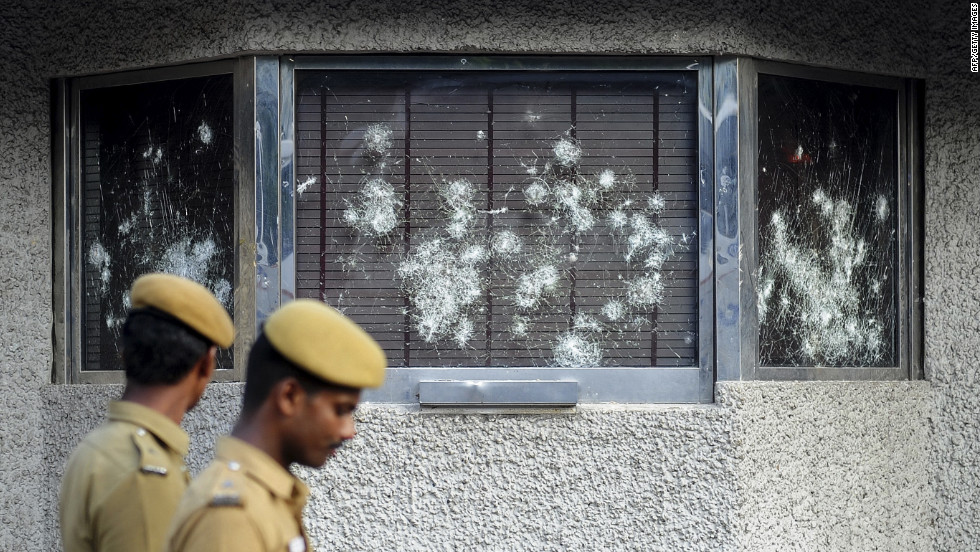 Indian policemen walk past smashed windows of the U.S. Consulate building, caused by a mob of demonstrators protesting against an anti-Islam film, in Chennai, India, on Friday, September 14.