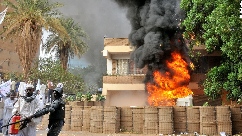 Smoke billows from the burning German Embassy in Khartoum, Sudan, as a policeman stands next to a man preparing to extinguish the fire caused by protesters the anti-Islam film. Around 5,000 protesters in the Sudanese capital stormed the embassies of Britain and Germany, which were torched and badly damaged.