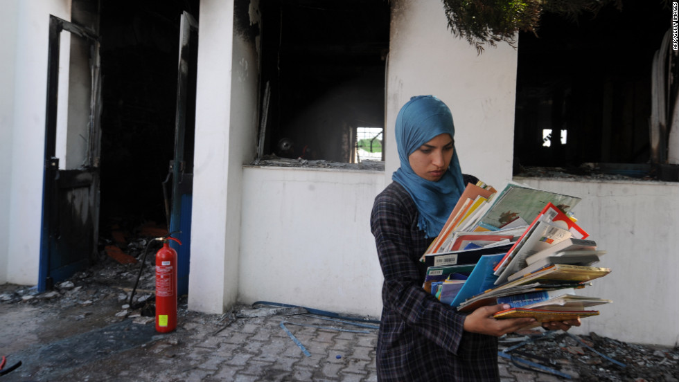 A  woman collects books from a classroom in the American school in Tunis on Saturday.