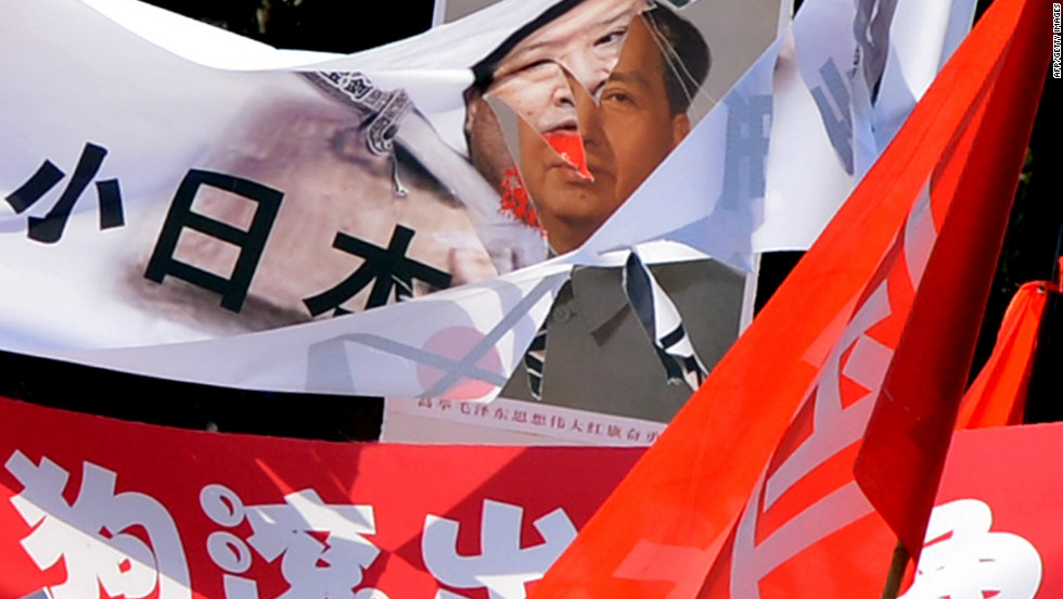 A shredded banner shows Japanese Prime Minister Yoshihiko Noda beside a picture of Mao Zedong in Beijing.