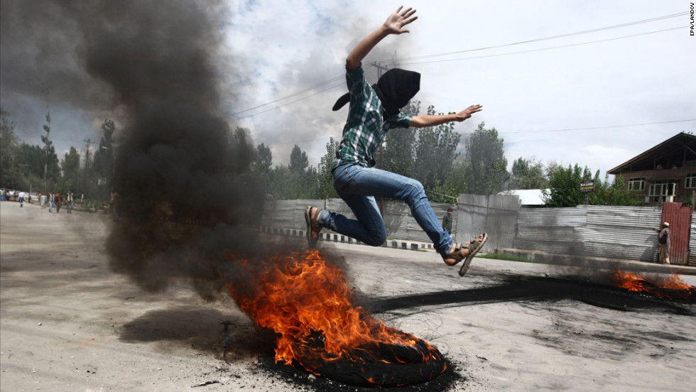 A Kashmiri Muslim boy jumps over a burning tire set up as a roadblock during Tuesday&#39;s demonstration Srinagar.