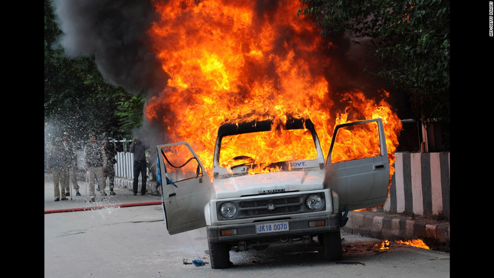 Firefighters attempt to extinguish the flames in an Indian police vehicle  as protesters clash with police during a protest and in Srinagar, Kashmir, on Tuesday.