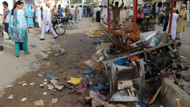 Local residents gather at the site of an overnight bomb explosion in Karachi on September 19, 2012. 