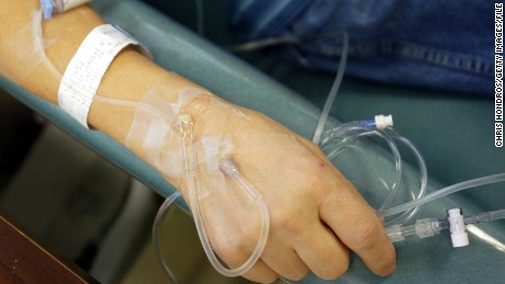 A cancer patient holds the IV tubes during chemotherapy.