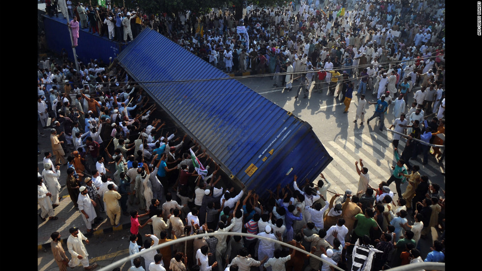 Pakistani Muslim demonstrators topple a freight container that was placed by police to block a street during a protest on Friday.