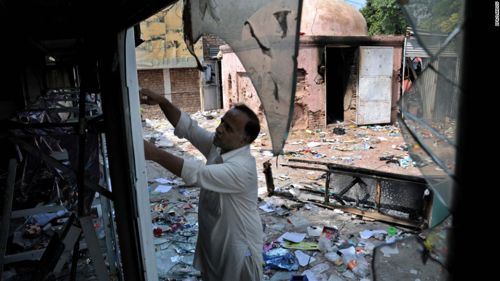 A worker inspects his damaged shop following violent protests in Peshawar, Pakistan, on Saturday.