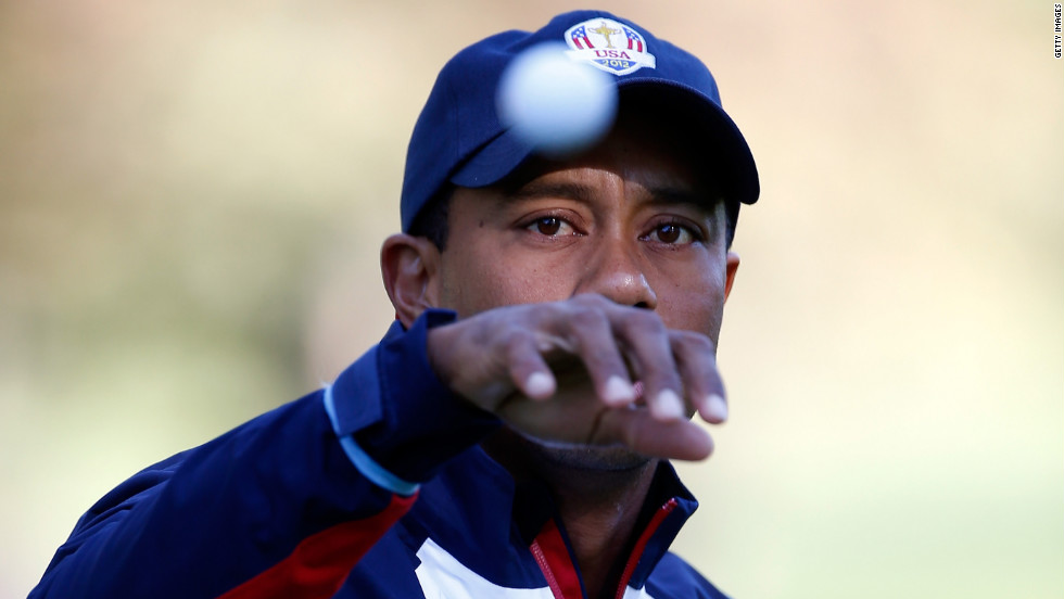 Team U.S.&#39;s Tiger Woods reaches for a golf ball on the practice ground on Thursday.