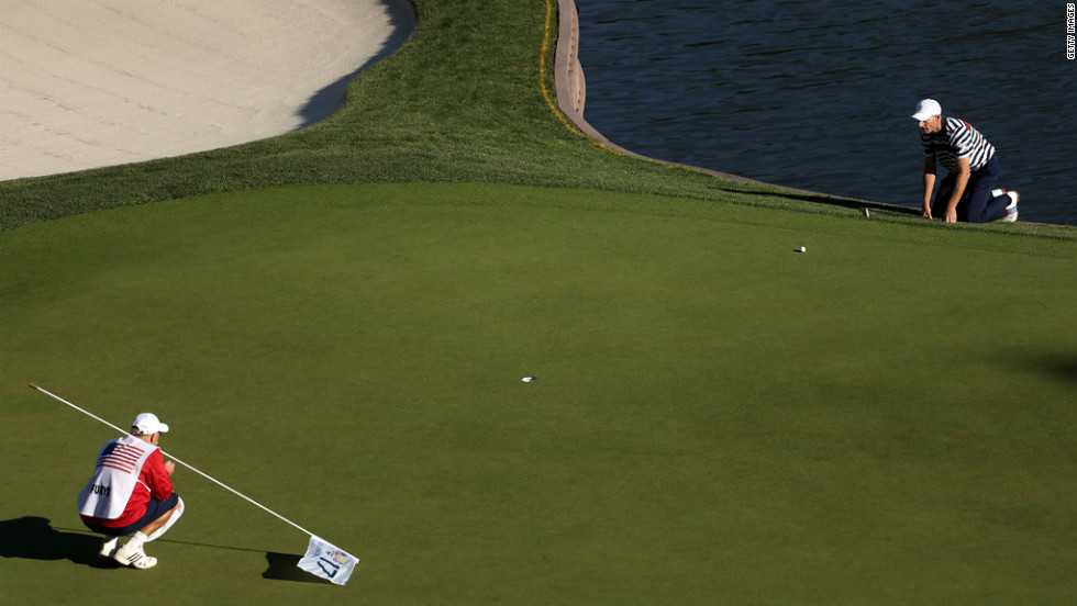 Jim Furyk of the United States lines up a putt with his caddie, Mike Cowan, on the 17th green.