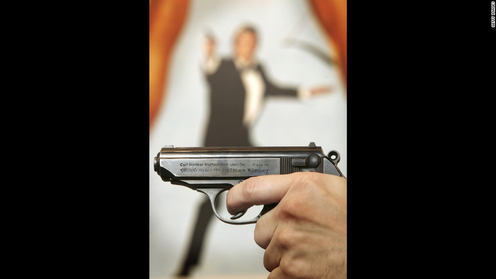  A Walther PPK handgun is held in front of a poster of the film &quot;For Your Eyes Only.&quot;