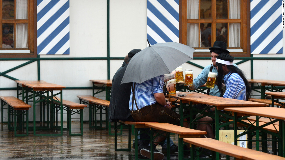 Visitors drink beer while rain falls on the Oktoberfest festival fairground on Sunday.