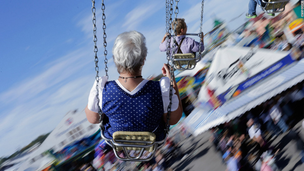 People dressed in traditional Bavarian clothing ride swings during Friday&#39;s festivities.