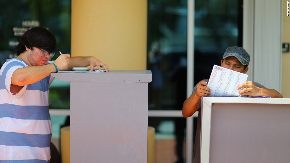 Allan Banojakedjian, left, and Jesus Romero fill out their voter registration forms at the Miami-Dade Elections Department on the final day of registration for the upcoming presidential election.