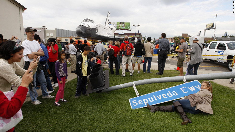 People pose with a street sign that was removed to make way for the space shuttle Endeavour during its transport from LAX to the California Science Center.