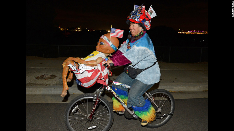 Fan Vivian Robinson rides her bicycle covered in shuttle memorabilia, American flags and an alien doll outside the Los Angeles airport as she waits to see Endeavour.