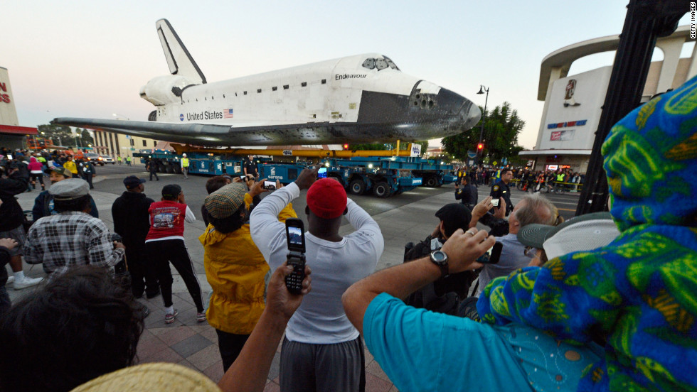 Crowds look on as Endeavour is transported to The Forum arena before sunrise on Saturday. 