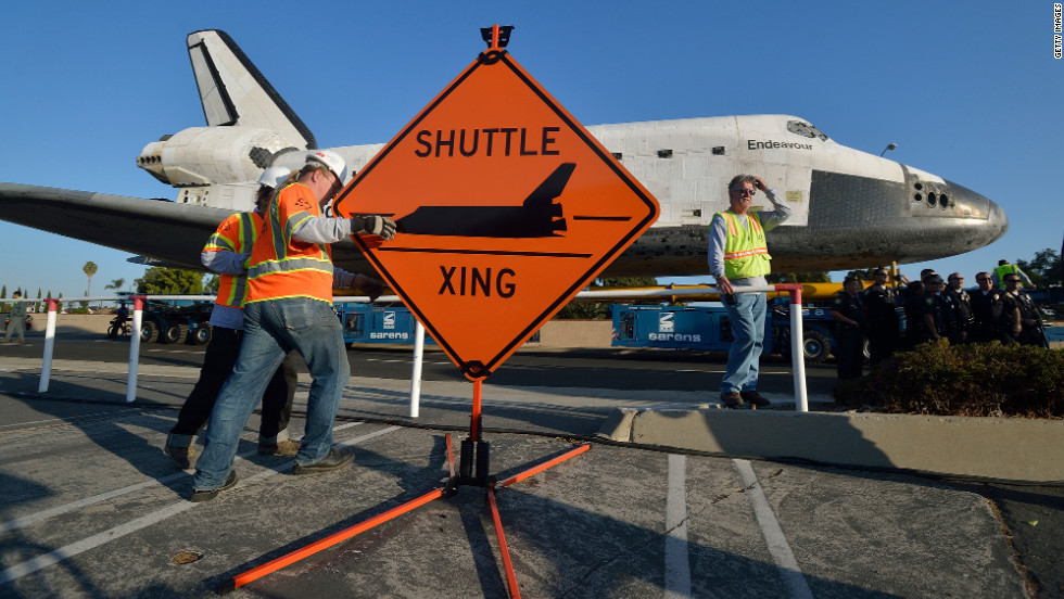 Work crews set up a &quot;Shuttle Xing&quot; sign on Saturday.