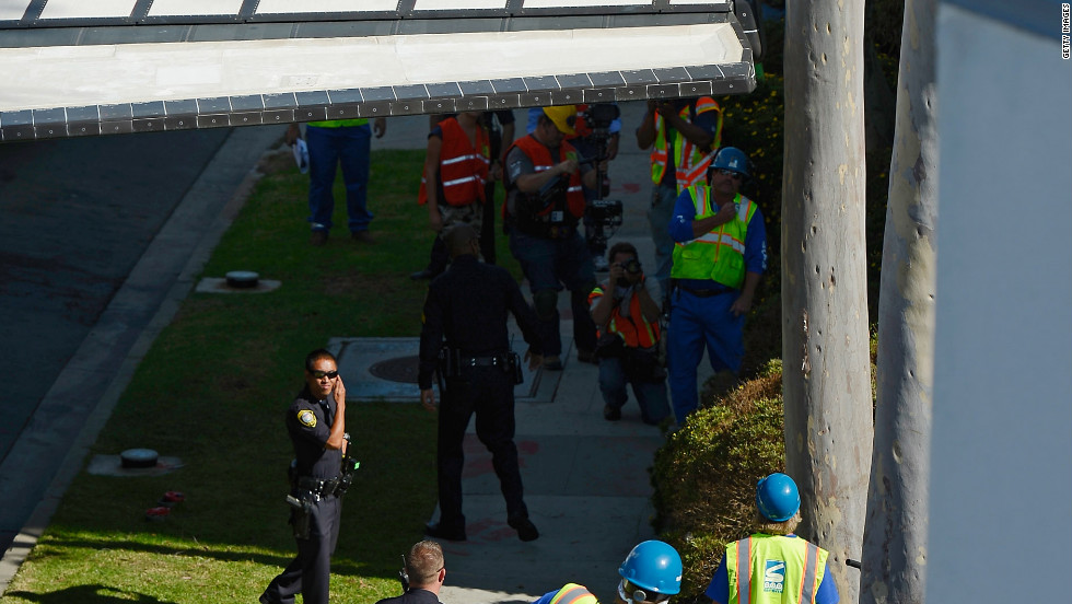 Workers and officials look on as Endeavour squeezes past a tree.