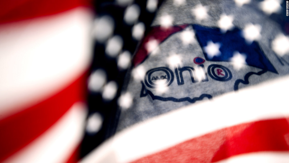 A supporter holds an American flag in front of the Ohio logo on his shirt as he stands with a crowd at Shawnee State University to hear Romney speak on Saturday.