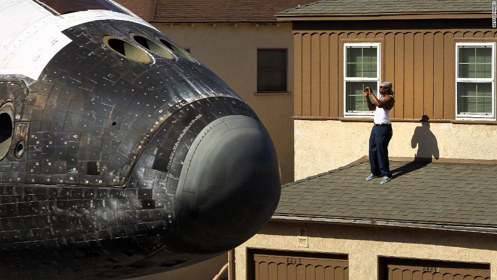 A man takes a picture from a rooftop as Endeavour makes its way toward the California Science Center on Saturday.