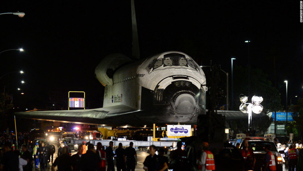 The space shuttle Endeavour makes its way down a city street under heavy escort on Saturday, October 13.