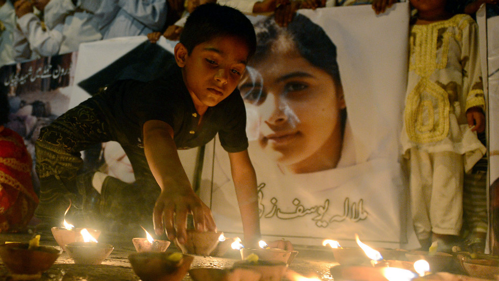 A Pakistani youth places an oil lamp next to a photograph of teen activist Malala Yousufzai on Friday, October 12, 2012, in Karachi, Pakistan. 