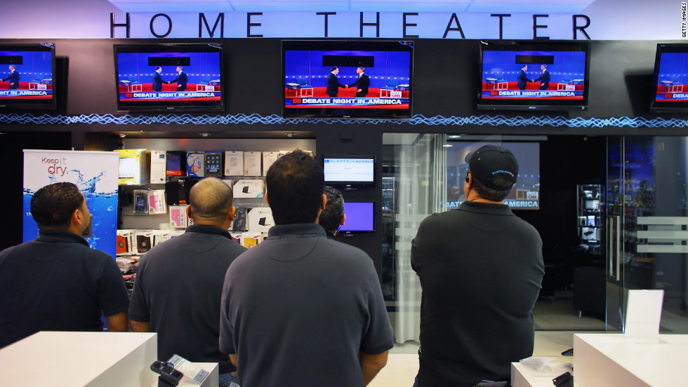 A group of men watch the presidential debate on television screens at an electronics store in Miami on Tuesday, October 16.