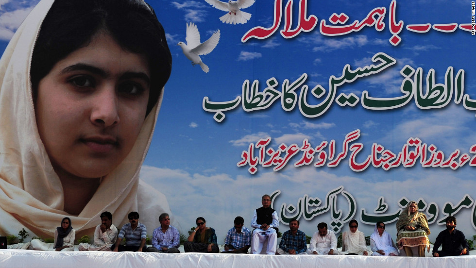 Pakistani leaders of the movement sit in front of a poster of Malala at a procession in Karachi.