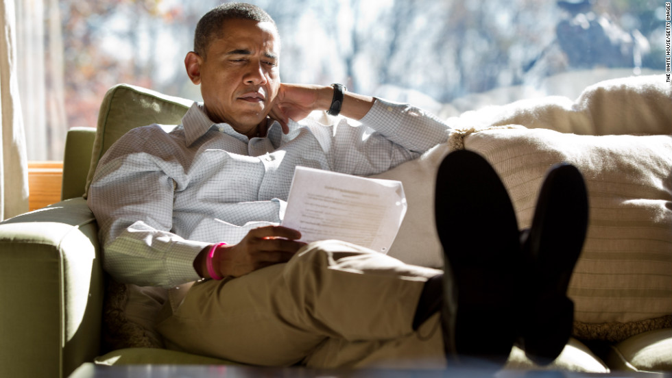 Obama reads briefing material while meeting with advisers inside his cabin on Sunday, October 21, at Camp David, Maryland. 