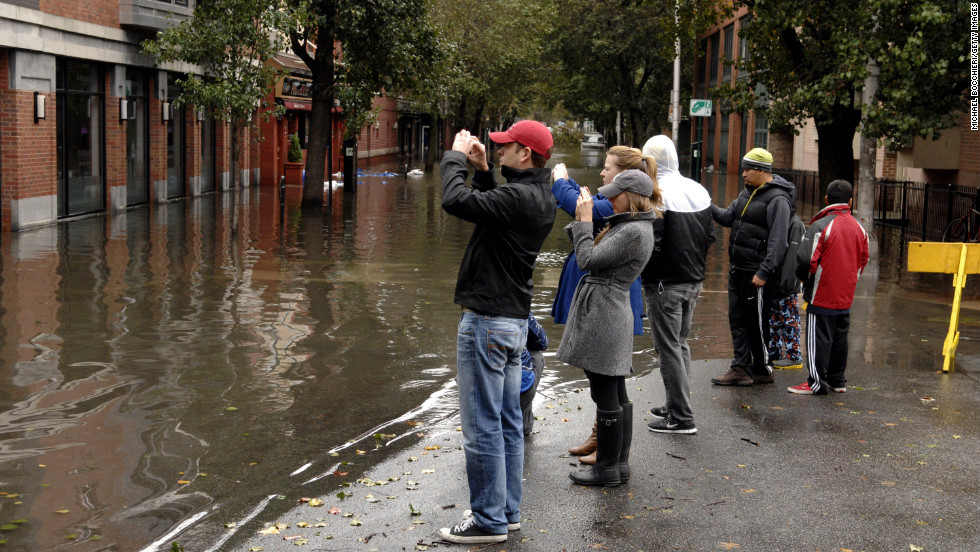 People take pictures of a flooded street Tuesday in Hoboken.