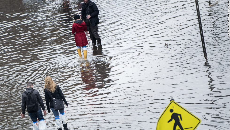 People walk down a flooded street on Wednesday, October 31, in Hoboken, New Jersey.  