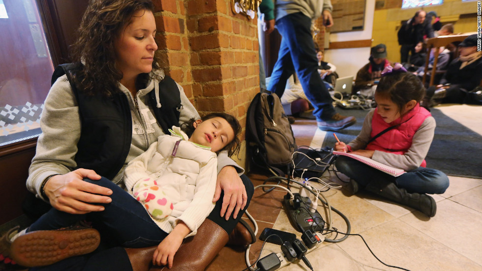 Bridget De La Torre holds her daughter Neve, 3, as daughter Paz sits nearby while they rest and charge devices on Thursday. They were at a shelter for those affected by Superstorm Sandy at Saints Peter and Paul Church in Hoboken, New Jersey. Bridget&#39;s family has no electricity or hot water, and their car was destroyed by flooding. 