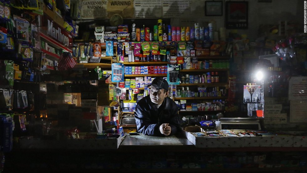 Park Choul works by flashlight in his deli in New York&#39;s East Village on Thursday, November 1. More than 3.3 million customers remained without electricity in 15 states and the District of Columbia four days after Sandy barreled ashore.