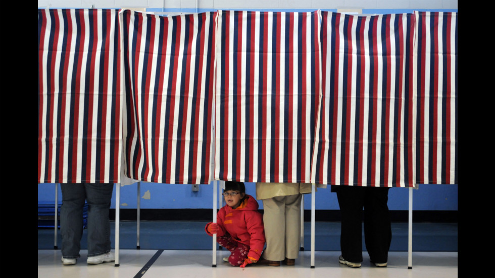 A young girl peered out from under a voting booth as her mother cast a ballot at the Bishop Leo O&#39;Neil Youth Center in Manchester, New Hampshire. 