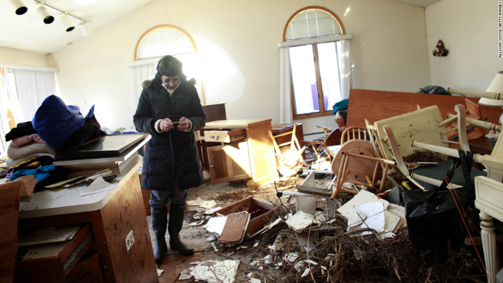 A woman sifts through her mother&#39;s damaged home for items to save Sunday in the Breezy Point neighborhood of Queens, New York.