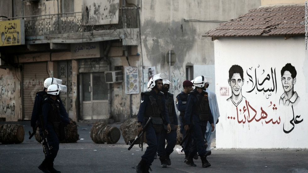 Bahraini riot policemen walk past graffiti reading in Arabic: &#39;Peace on our martyrs&#39; as they try to disperse protesters. The teenager was killed as police attempted to stop pposition supporters from joining a mass during weekly Friday prayers. 