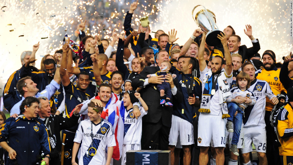 Galaxy captain Landon Donovan holds up the MLS Trophy as David Beckham, lower left, and other teammates celebrate their win.