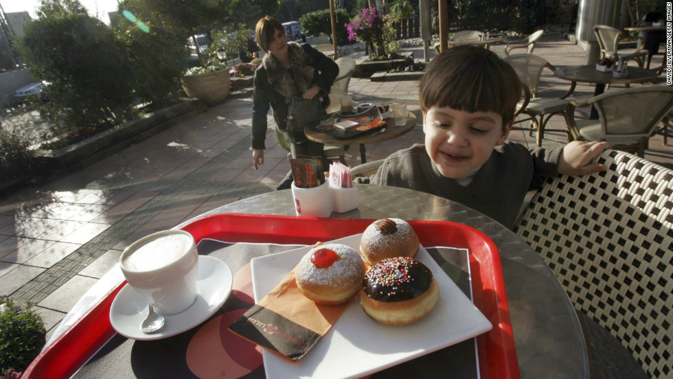 A young Israeli boy looks at a serving of fresh oil-fried and jam-filled doughnuts, known in Hebrew as &quot;sufganiyot&quot;, served at one of the local bakeries in Kadima, central Israel, during Hanukkah.