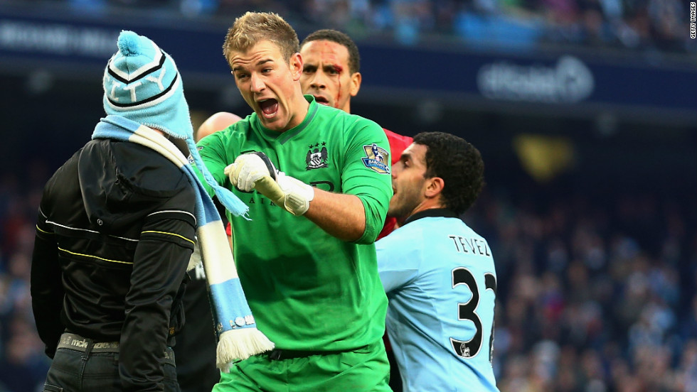 Manchester City goalkeeper Joe Hart of  confronts a pitch invader at the end of his side&#39;s 3-2 derby defeat by Manchester United, whose defender Rio Ferdinand (at back) was left with a bloody face after being hit by a coin thrown from the crowd. 