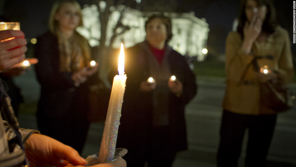 Candles burn as people gather for a vigil outside the White House.