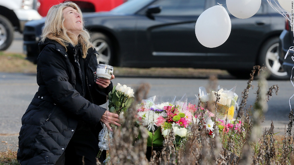 Andrea Jaeger places flowers and a candle at a makeshift memorial outside a firehouse near Sandy Hook Elementary School on Saturday.