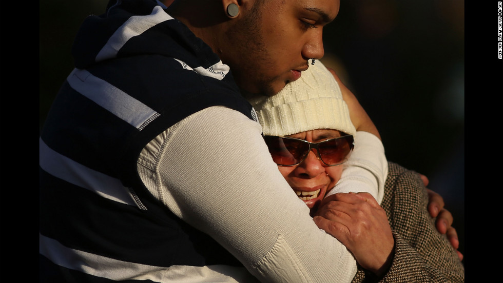 Zulma Sein is hugged by a family member outside of the entrance to the Sandy Hook School on Saturday.