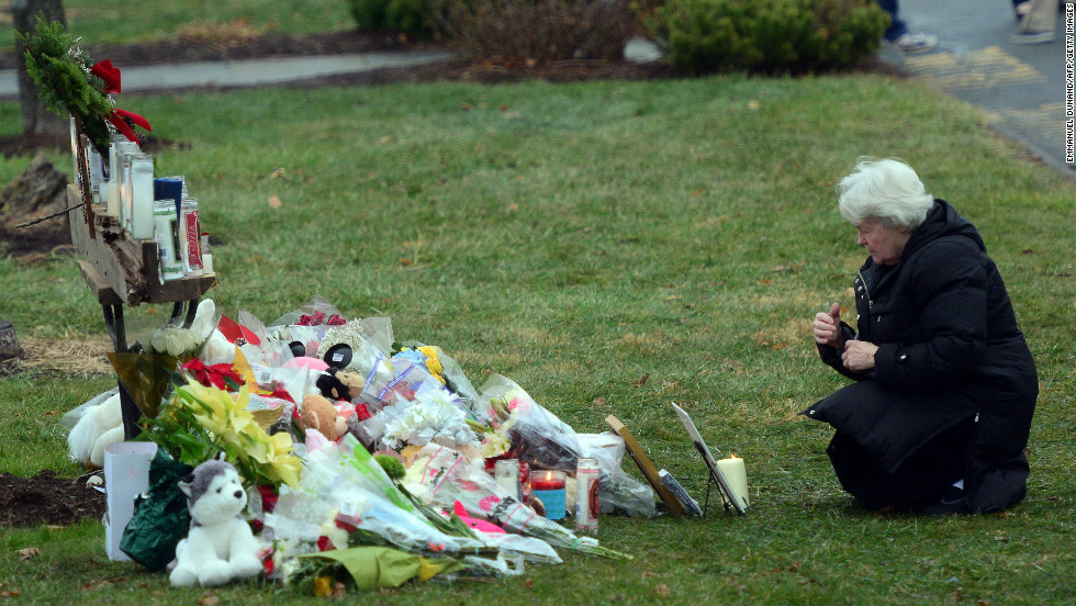 A parishioner kneels in front of a makeshift memorial at St. Rose of Lima Roman Catholic Church in Newtown on December 16.