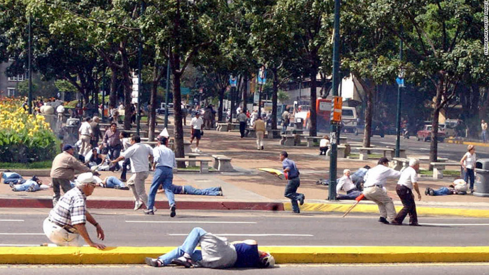 People try to take shelter from gunshots fired near Altamira Square in Caracas on August 16, 2004. At least three people were wounded by gunshots after Chavez supporters fired on opposition demonstrators, police said. A vote to recall Chavez as president failed on August 15.