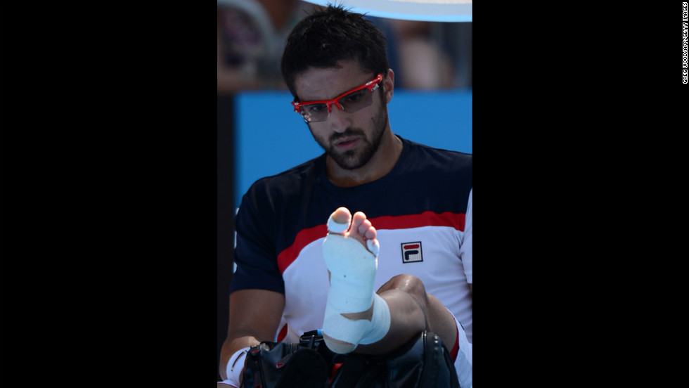 Serbia&#39;s Janko Tipsarevic looks at his wrapped foot during a break in his men&#39;s singles match against Spain&#39;s Nicolas Almagro on January 20. Almagro moved on to the next round after Tipsarevic pulled out of the match in the second set because of his injury.