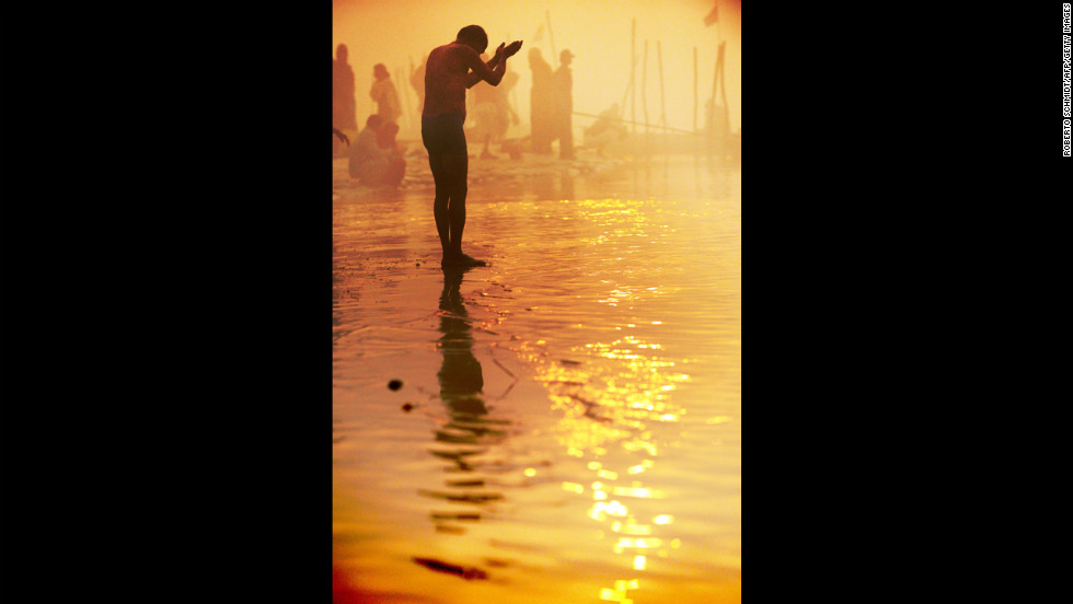 A devotee prays at day break while taking a dip at the Sangam on January 13.