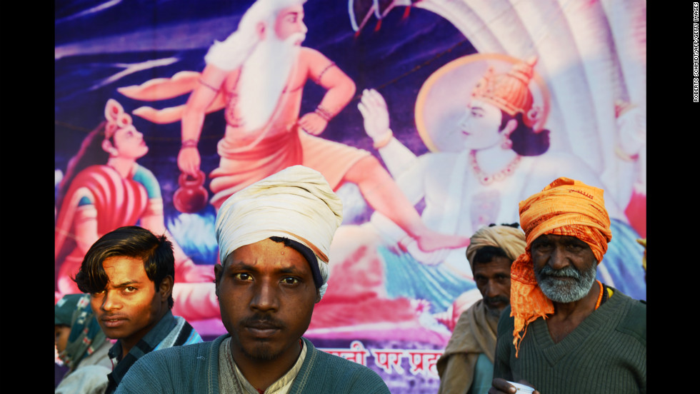 Indian devotees stand in front of a painting depicting Hindu gods during the Maha Kumbh Mela festival on February 8.