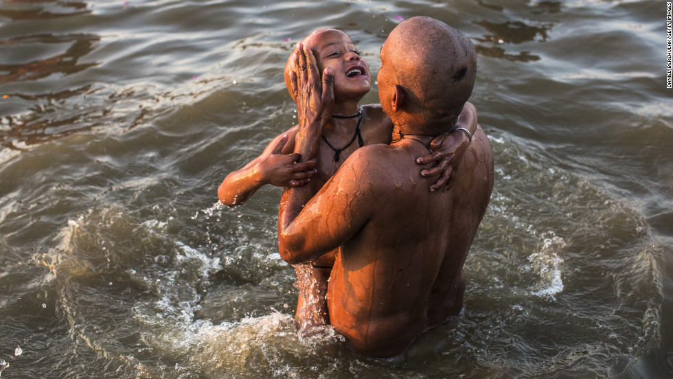 A father lifts his son out of the waters of the Sangam on Friday, February 8.