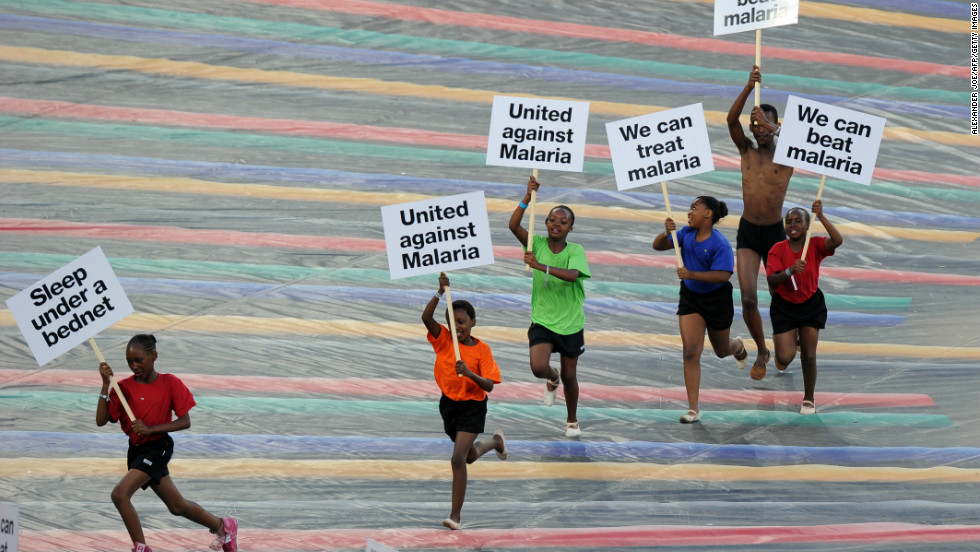 Children run with advertising banners highlighting the fight against malaria during a ceremony held ahead of the final.