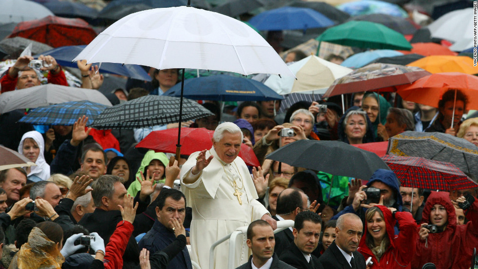 Benedict waves from under an umbrella as he arrives to lead his weekly general audience in Saint Peter&#39;s Square at the Vatican in October 2007.