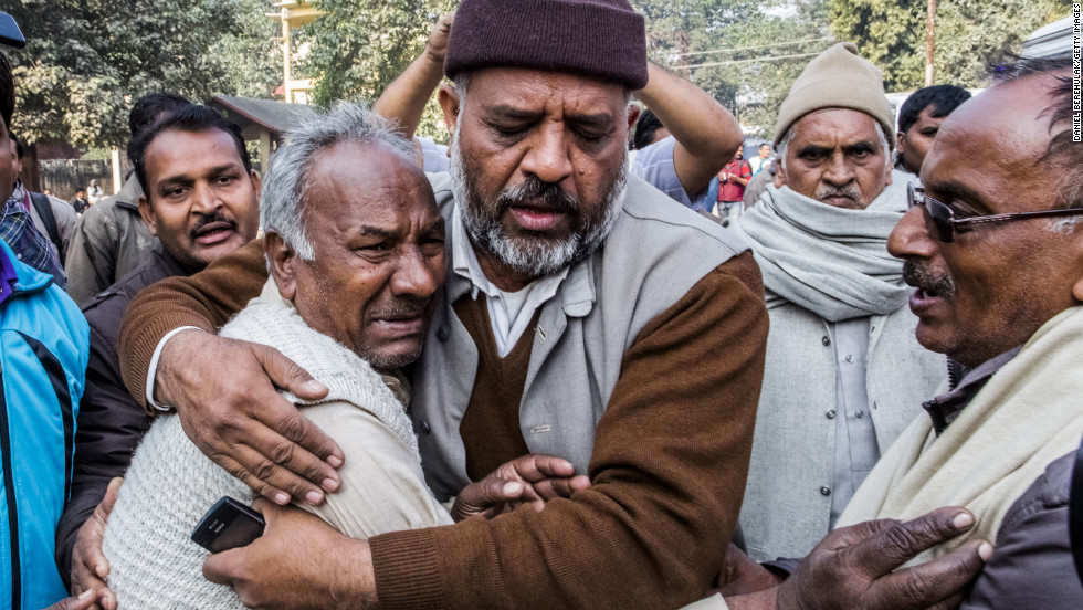 Men grieve on February 11, after a railroad station crush that left 36 people dead Sunday at the Kumbh Mela festival in Allahabad, India. 